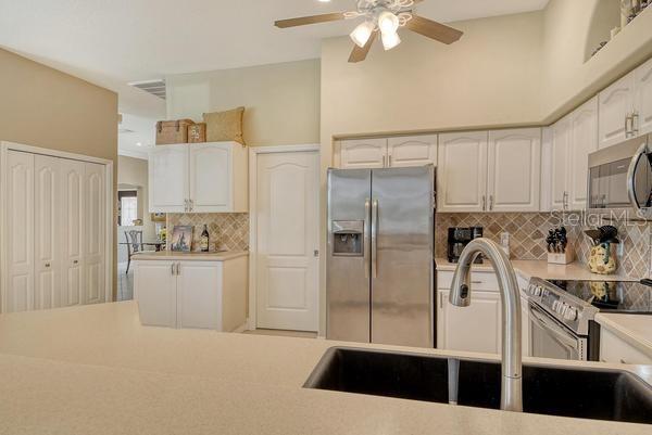 9477 Cedar Ridge Lane Sarasota, FL 34238 - Photo 9 of 51 a kitchen with stainless steel appliances a refrigerator sink and cabinets