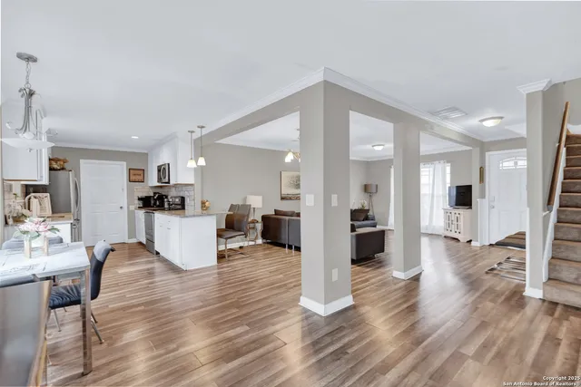 a living room with furniture a wooden floor and a kitchen view