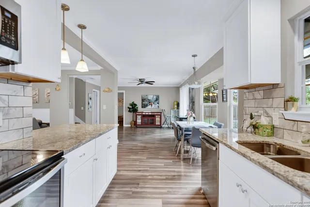 a kitchen with stainless steel appliances granite countertop a sink counter space and living room view