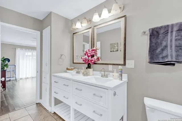 a bathroom with a double vanity sink mirror and toilet