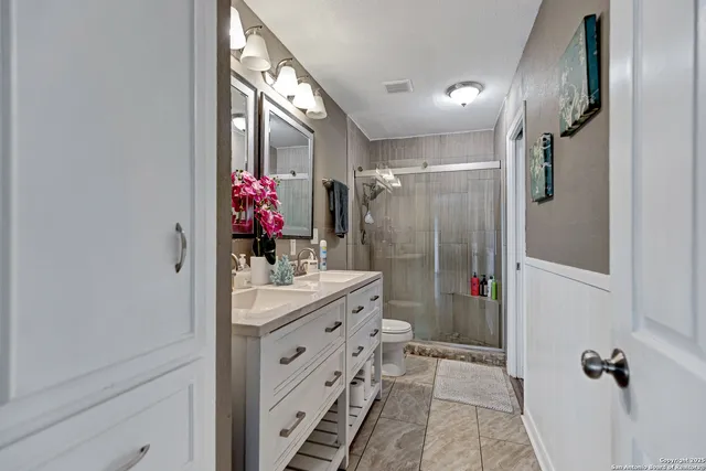 a bathroom with a double vanity sink mirror and shower
