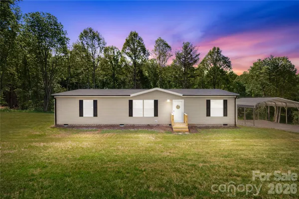 a house that is sitting in the grass with large trees