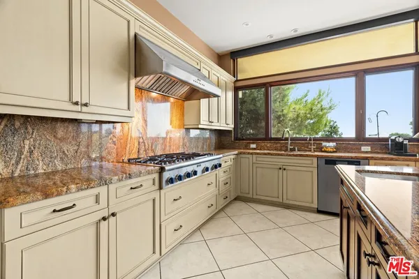 a kitchen with stainless steel appliances granite countertop a stove a sink and a refrigerator