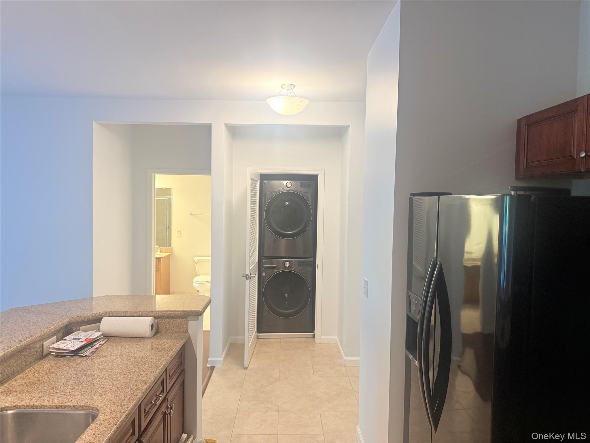 935 Tower Ridge Circle Middletown, NY 10941 - Photo 16 of 24 Built-in stacked washer and dryer unit, complemented by a stainless steel refrigerator and wood-finish cabinetry
