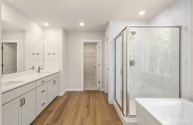 a spacious bathroom with a granite countertop sink a mirror a bathtub and shower