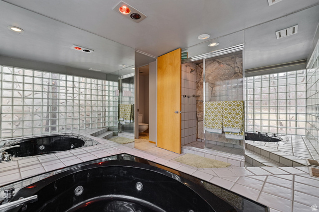 1856 Fort Canyon Road Alpine, UT 84004 - Photo 37 of 49 Bathroom featuring a black corner soaking tub with jetted features, a glass block wall, and white tile flooring