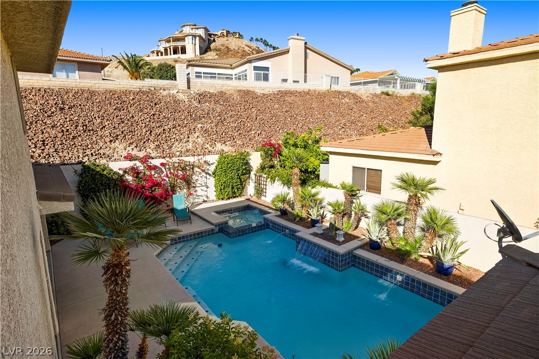 1135 Calico Ridge Drive Henderson, NV 89011 - Photo 46 of 86 A private backyard oasis features a glistening pool and spa, set against a desert landscape with mature palms.