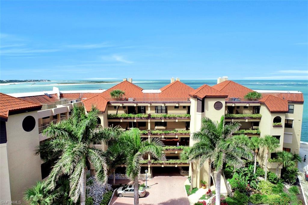 623 La Peninsula Boulevard, Unit 623 Naples, FL 34113 - Photo 1 of 27 a view of a white house with a yard and table and chairs under an umbrella