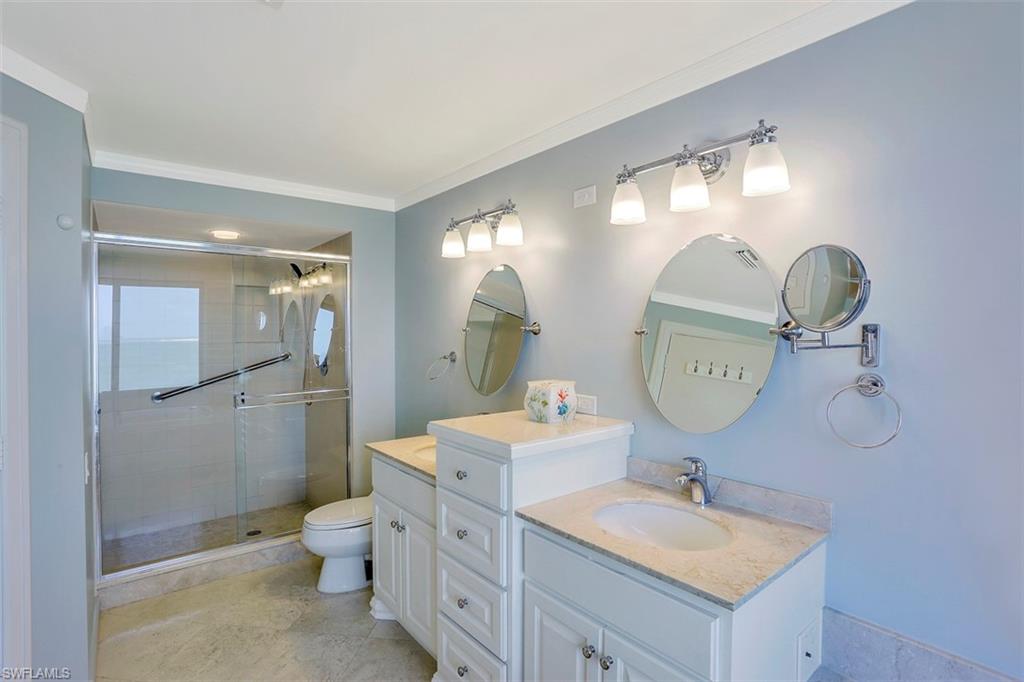623 La Peninsula Boulevard, Unit 623 Naples, FL 34113 - Photo 21 of 27 a bathroom with a double vanity sink toilet mirror and shower