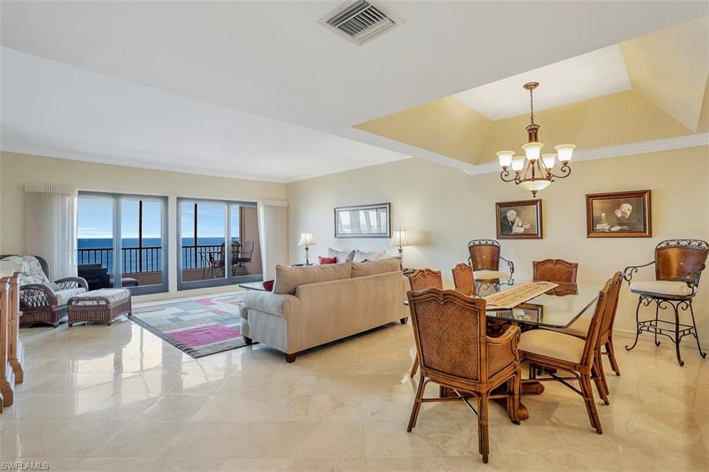 623 La Peninsula Boulevard, Unit 623 Naples, FL 34113 - Photo 9 of 27 a living room with furniture and a chandelier