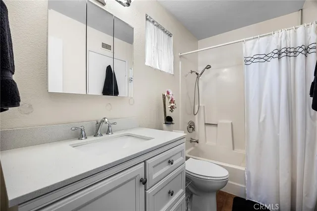 a bathroom with a sink a toilet a mirror and shower