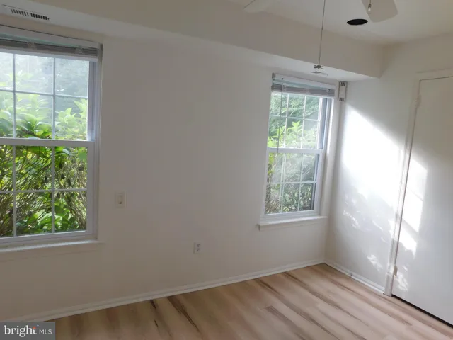a view of an empty room with wooden floor and windows