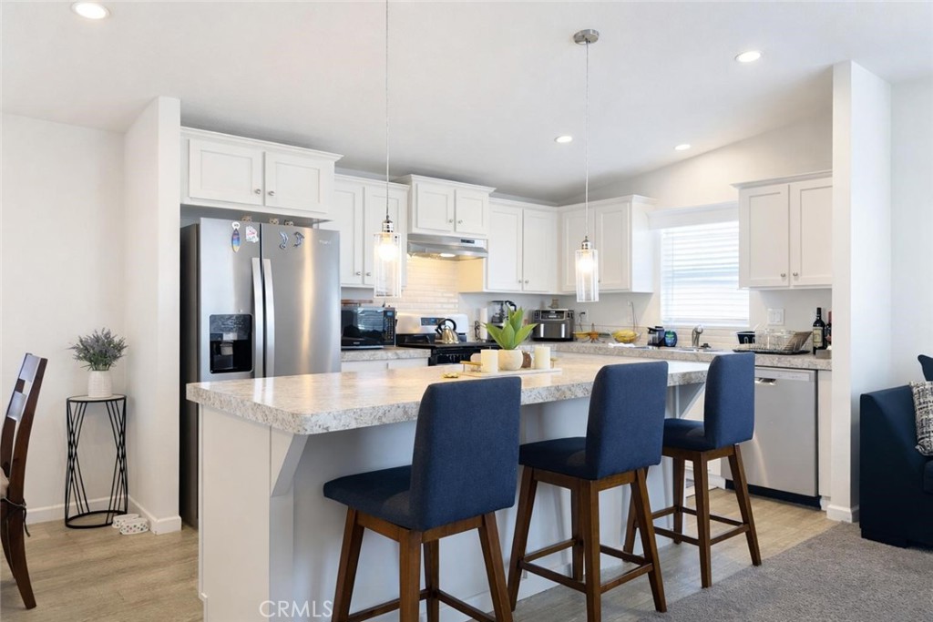 16600 Orange Avenue, Unit 130 Paramount, CA 90723 - Photo 10 of 31 a kitchen with stainless steel appliances granite countertop a dining table chairs refrigerator and sink