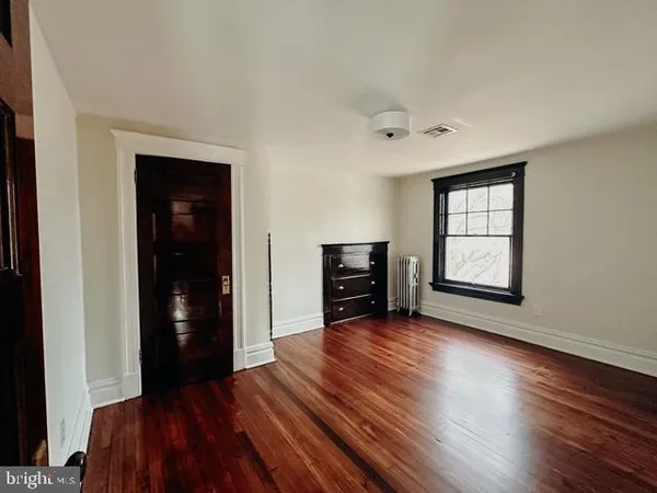 an empty room with wooden floor closet and windows