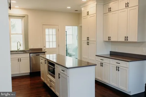 a kitchen with stainless steel appliances white cabinets and wooden floor
