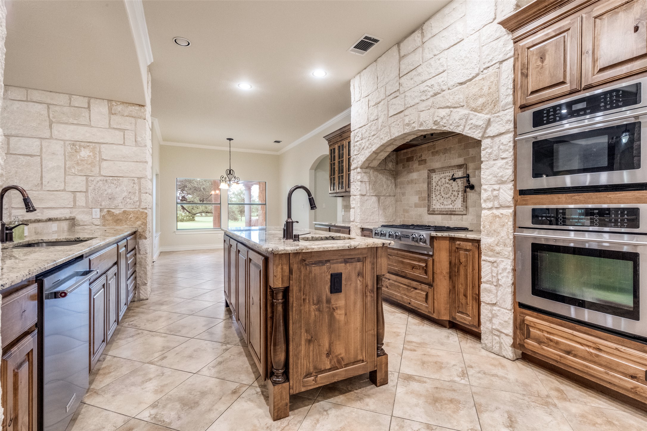 101 Copper Leaf Court Georgetown, TX 78633 - Photo 12 of 31 Gourmet kitchen featuring stone accent walls, integrated stainless steel appliances, and wood cabinetry