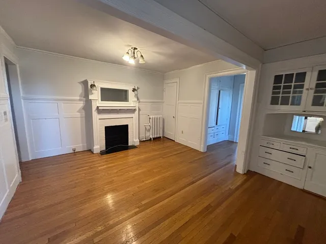 a view of empty room with wooden floor and fireplace