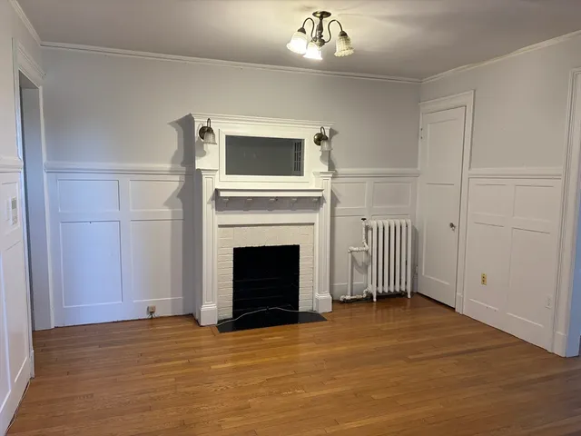 a view of a livingroom with a fireplace a ceiling fan and refrigerator