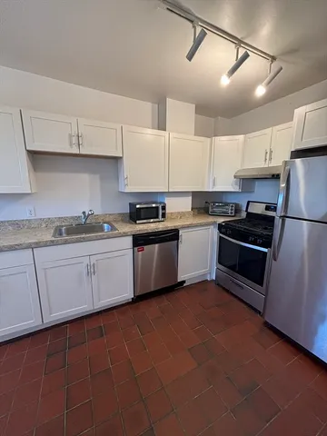 a kitchen with cabinets a sink and white appliances