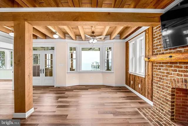 a view of an empty room with wooden floor and fan