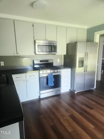 a kitchen with stainless steel appliances a stove a refrigerator and a microwave