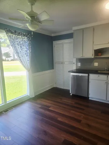 a view of an empty room with a window and wooden floor