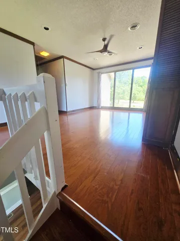 a view of an empty room with wooden floor and windows