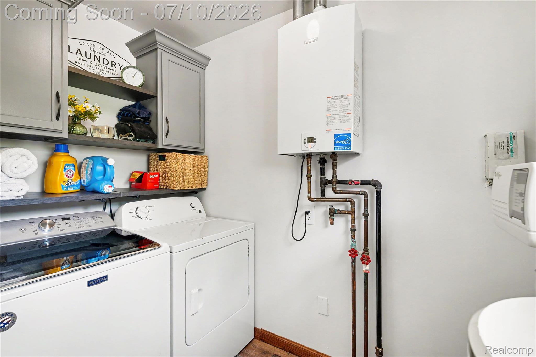 2180 Hurst Road St. Clair, MI 48079 - Photo 26 of 39 Utility area featuring a wall-mounted water heater, gray cabinetry, built-in shelving, and wood-finish flooring
