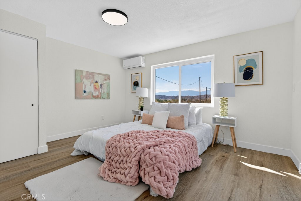 22700 Tamyran Road Desert Hot Springs, CA 92241 - Photo 32 of 65 a bedroom with a bed and wooden floor