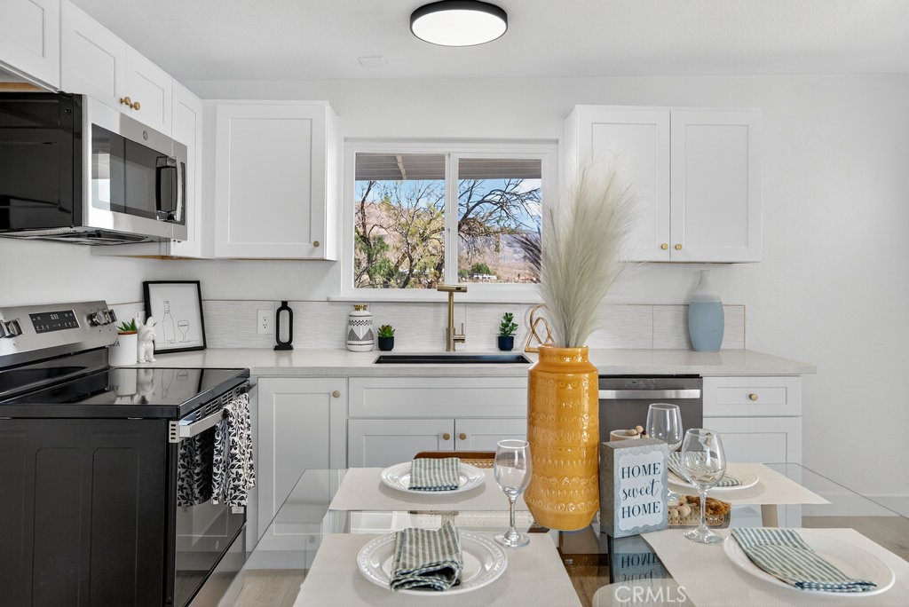 22700 Tamyran Road Desert Hot Springs, CA 92241 - Photo 8 of 65 a kitchen with stainless steel appliances a sink a stove cabinets and a window
