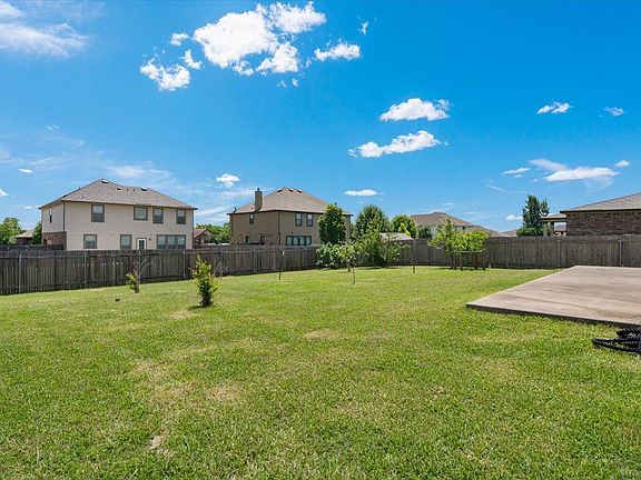 904 Lonesome Lilly Way Pflugerville, TX 78660 - Photo 32 of 34 The property features an extensive green lawn, a wooden fence, and a concrete patio area, all under a clear blue sky