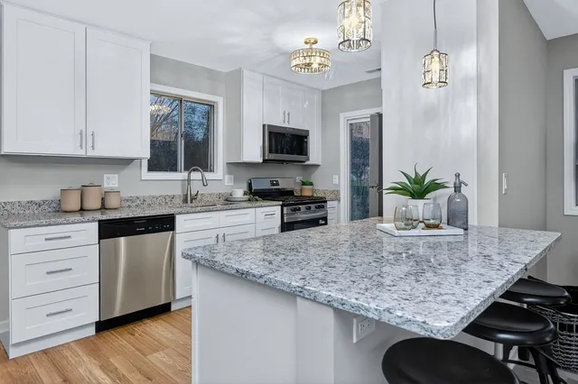 a kitchen with granite countertop kitchen island white cabinets and stainless steel appliances