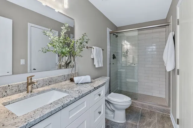 a bathroom with a granite countertop sink toilet a large mirror and shower
