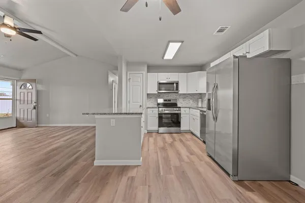 a kitchen with wooden floors white cabinets and stainless steel appliances