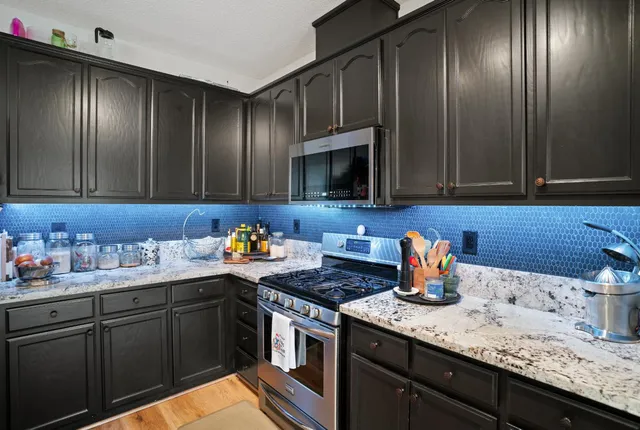 a kitchen with stainless steel appliances a dining table chairs refrigerator and sink