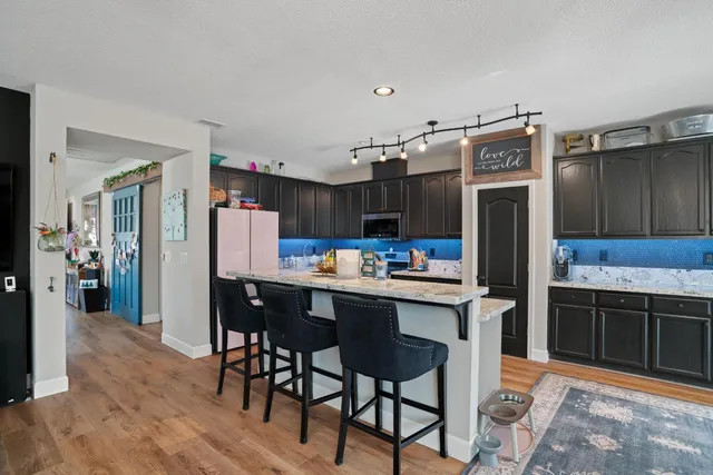 a kitchen with stainless steel appliances granite countertop a stove top oven a sink dishwasher and chairs with wooden floor