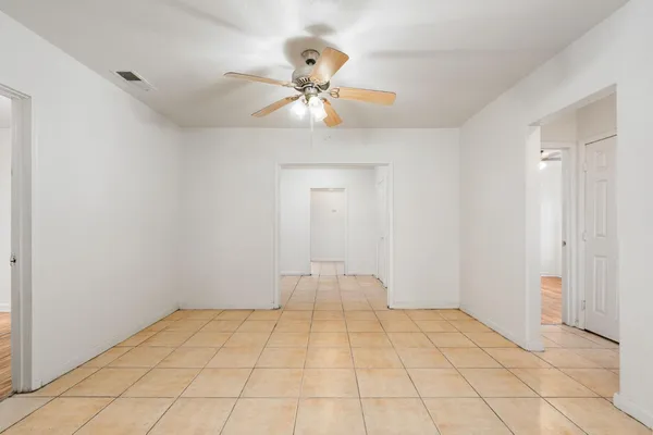 a view of an empty room and chandelier fan
