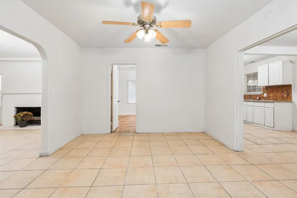 a view of an empty room and window with a kitchen