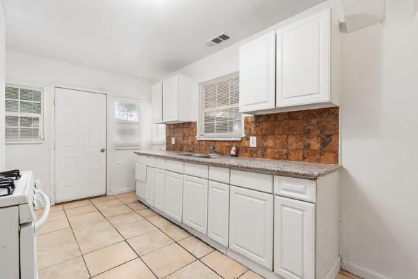 a kitchen with granite countertop white cabinets and white appliances