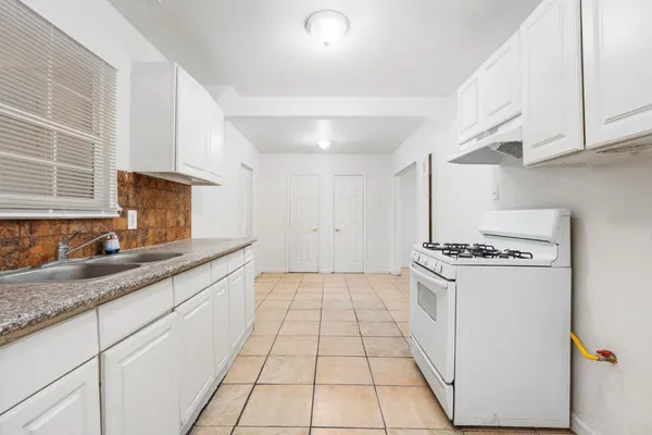 a kitchen with granite countertop a sink a stove and refrigerator
