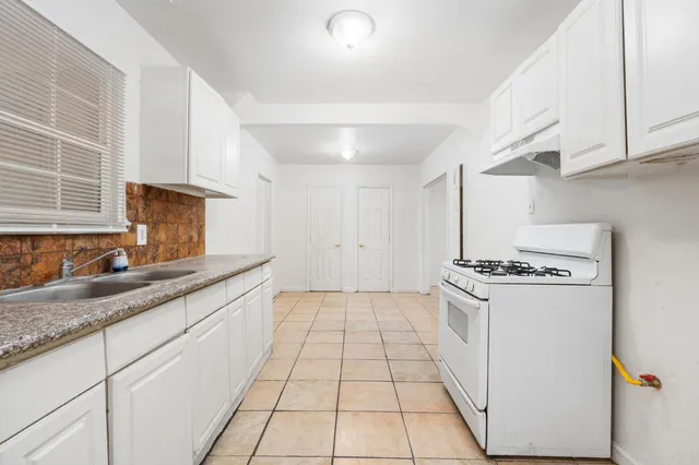 a kitchen with granite countertop a sink a stove and refrigerator