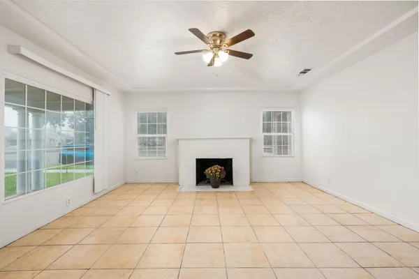 a view of an empty room with window and chandelier fan
