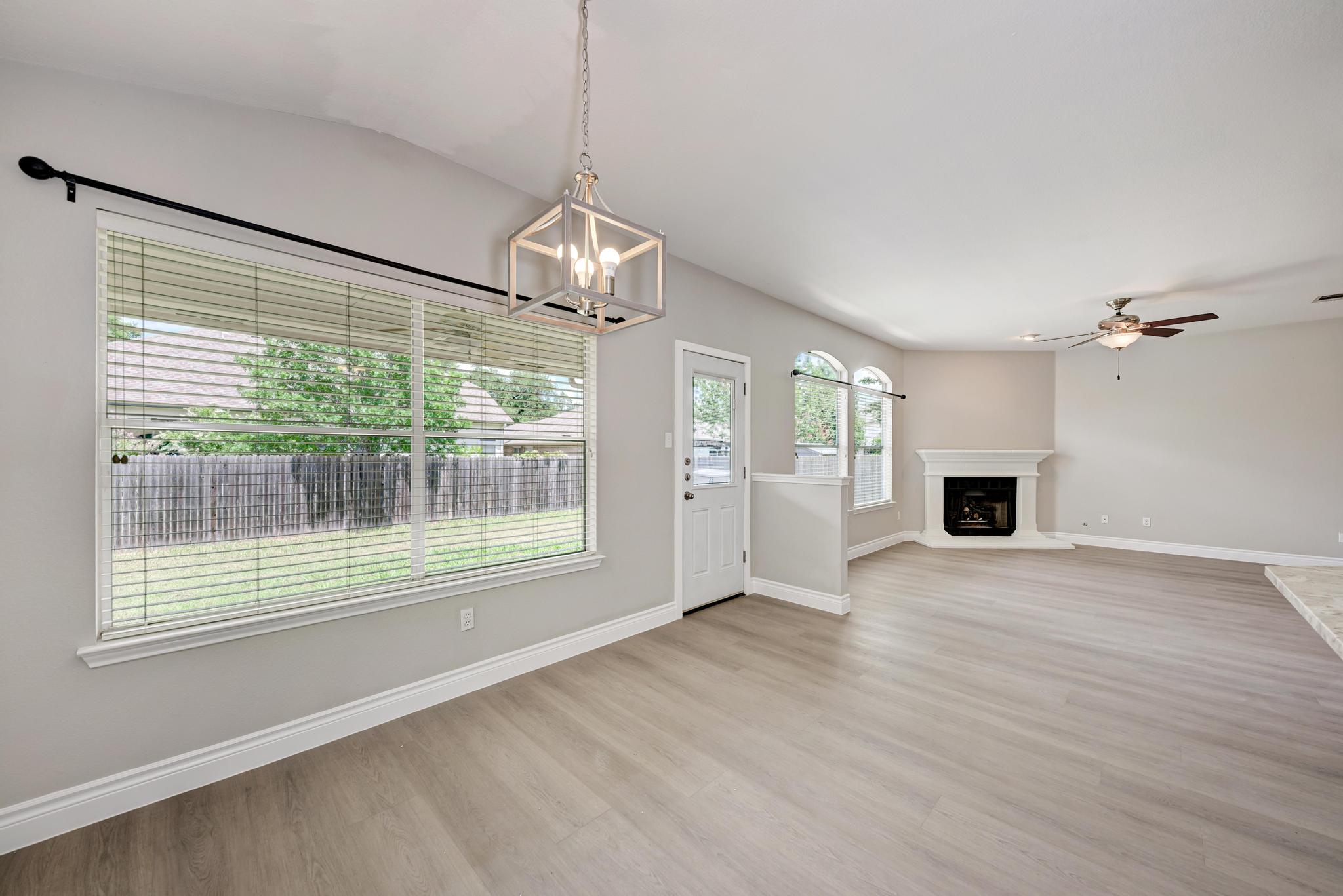 4408 Tello Path Austin, TX 78749 - Photo 13 of 38 Unfurnished living room with light wood-style floors, ceiling fan, a chandelier, a fireplace with raised hearth, and vaulted ceiling