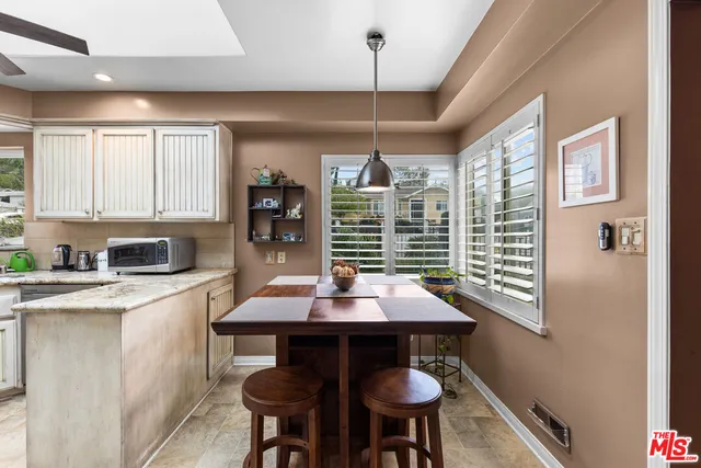 a dinning room with stainless steel appliances granite countertop furniture and a window