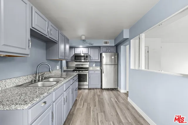 a kitchen with granite countertop a sink stainless steel appliances and cabinets
