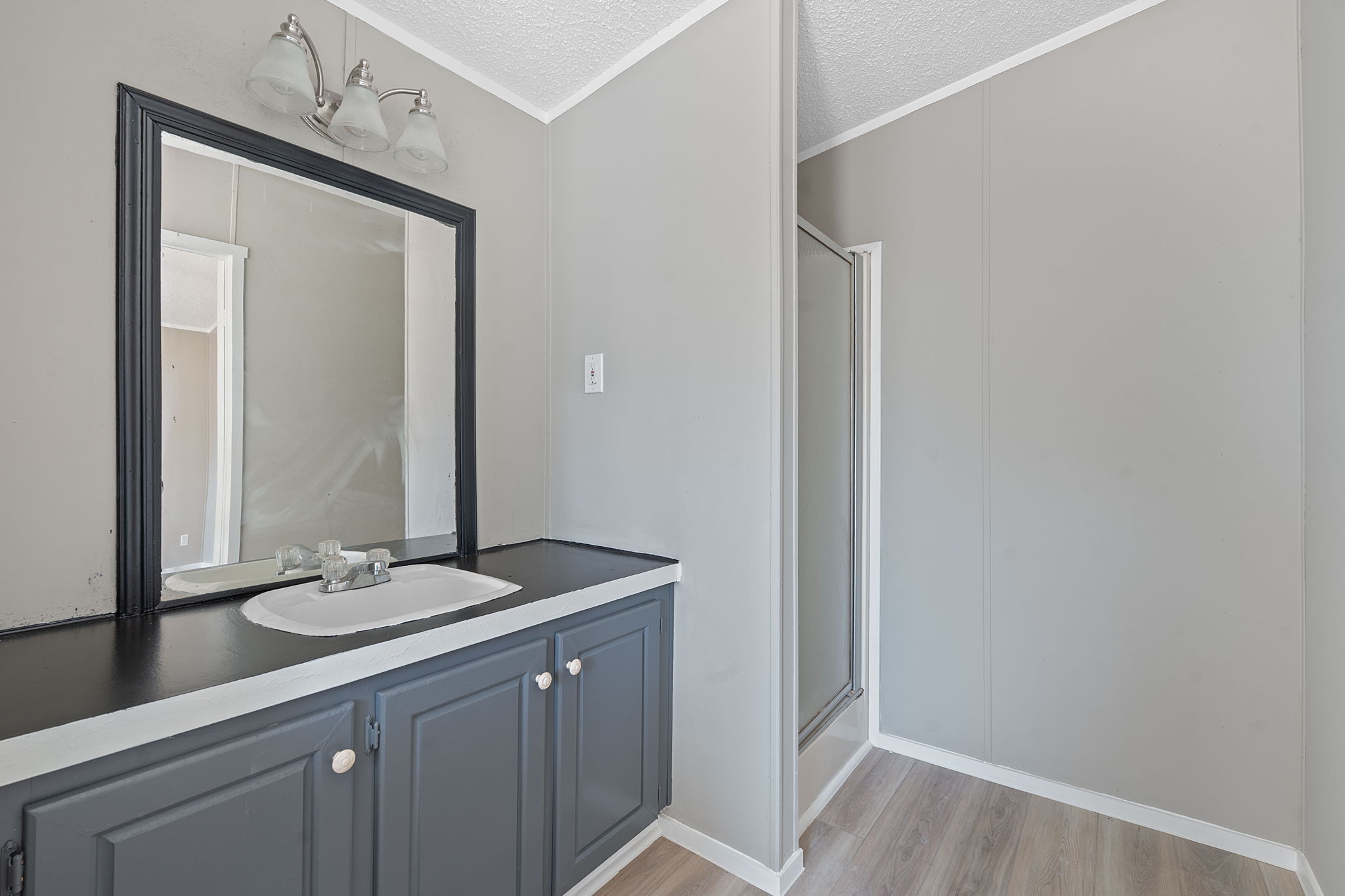 1385 Pettytown Road Dale, TX 78616 - Photo 11 of 27 Bathroom featuring a shower stall, a textured ceiling, light wood-style floors, vanity, and crown molding