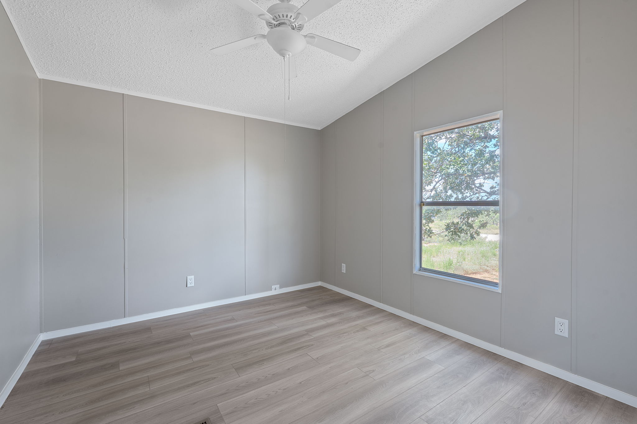 1385 Pettytown Road Dale, TX 78616 - Photo 13 of 27 Empty room with a decorative wall, light wood-style flooring, a textured ceiling, and ceiling fan