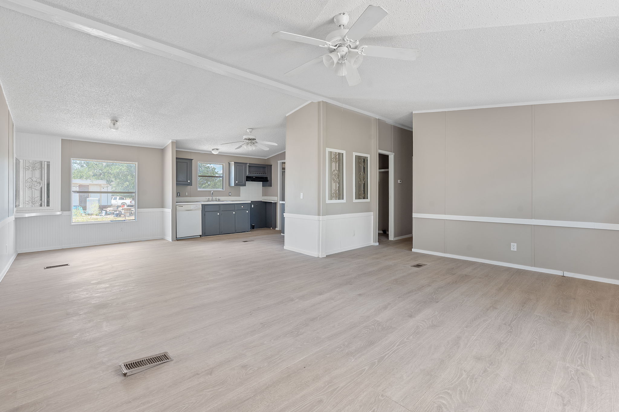 1385 Pettytown Road Dale, TX 78616 - Photo 3 of 27 Unfurnished living room featuring light wood-style flooring, a decorative wall, a textured ceiling, and ceiling fan