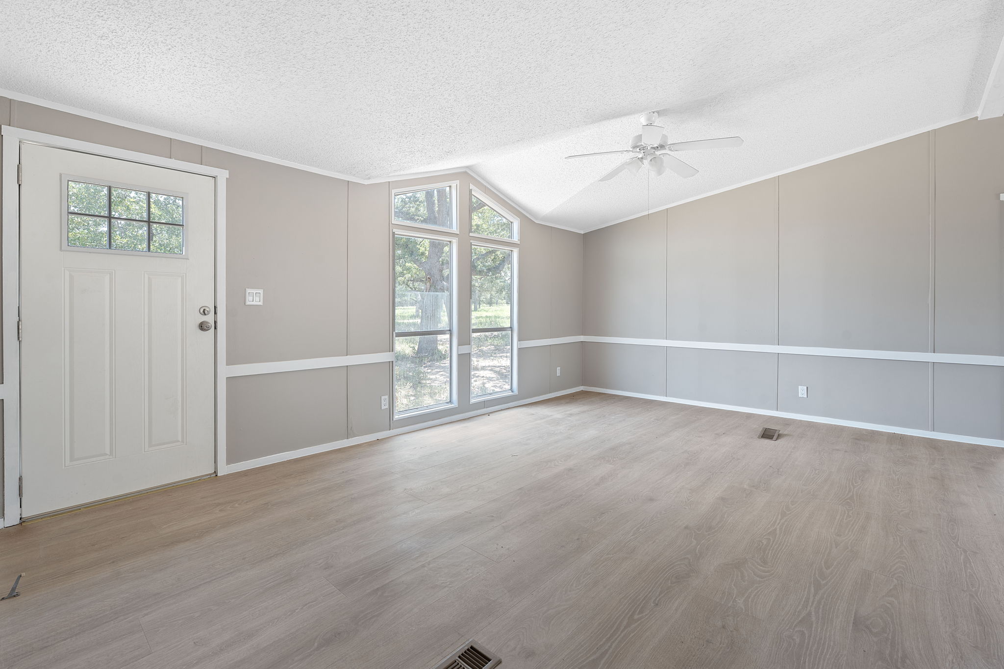 1385 Pettytown Road Dale, TX 78616 - Photo 4 of 27 Unfurnished living room featuring light wood-style floors, a decorative wall, crown molding, a textured ceiling, and a ceiling fan