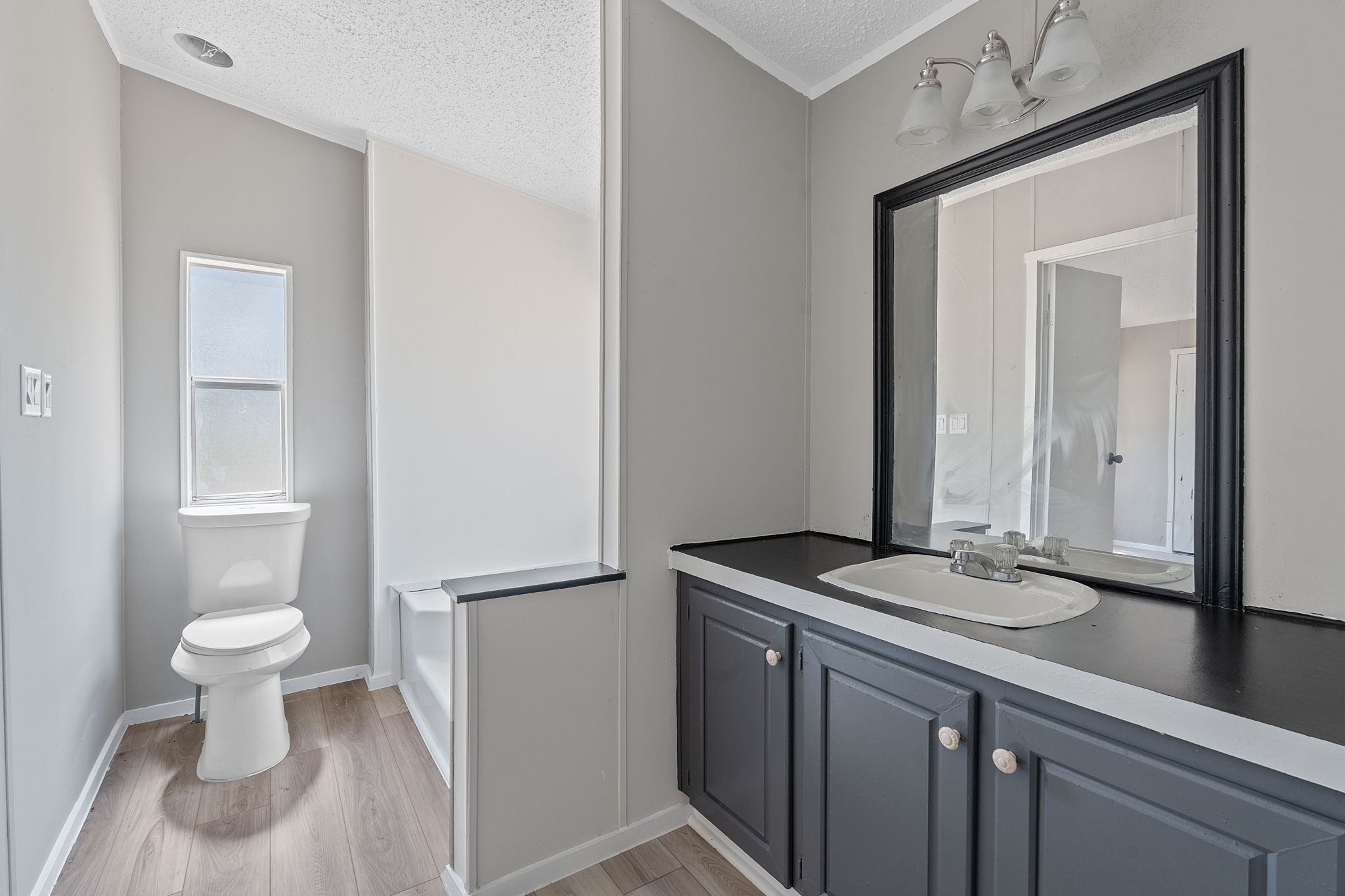1385 Pettytown Road Dale, TX 78616 - Photo 10 of 27 Full bathroom featuring light wood-type flooring, vanity, and a textured ceiling